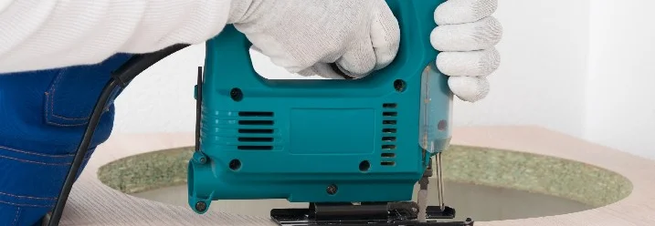 Person sägt mit Stichsäge in Holzplatte